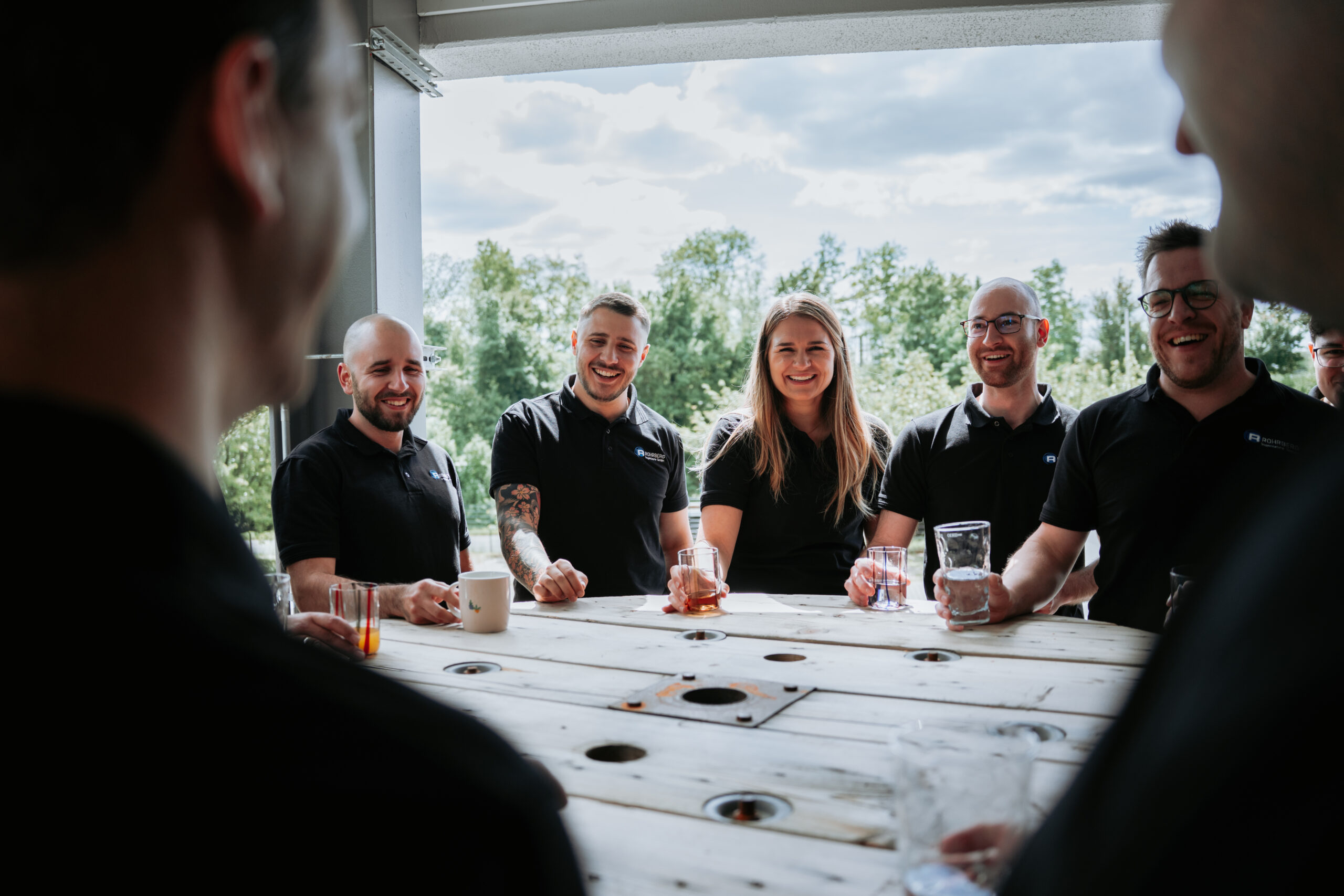 Nettes Beisammensein mit Getränken und mehreren Personen, die Getränke in der Hand halten und lächeln.
